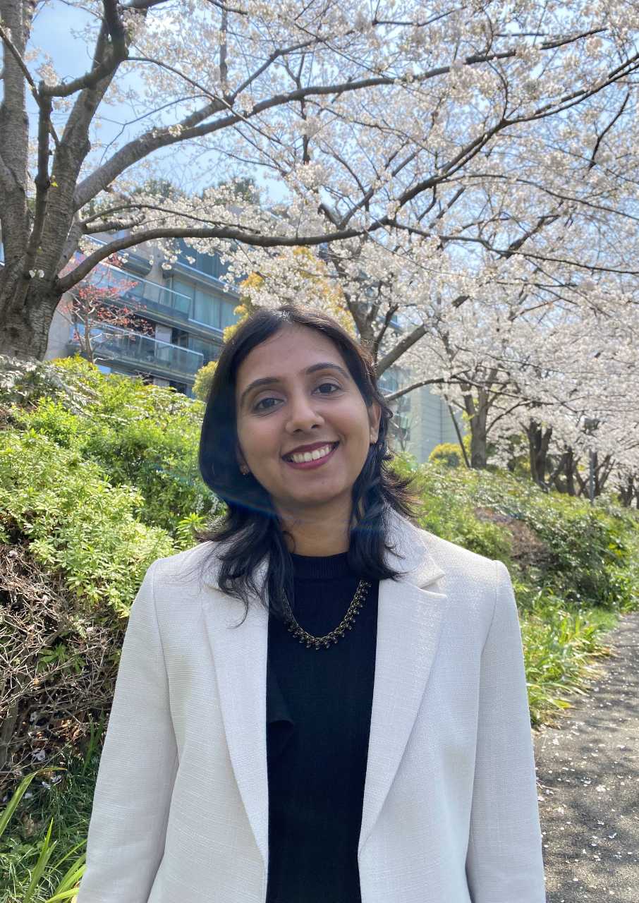Smruthi in formal attire standing in front of Cherry Blossom trees